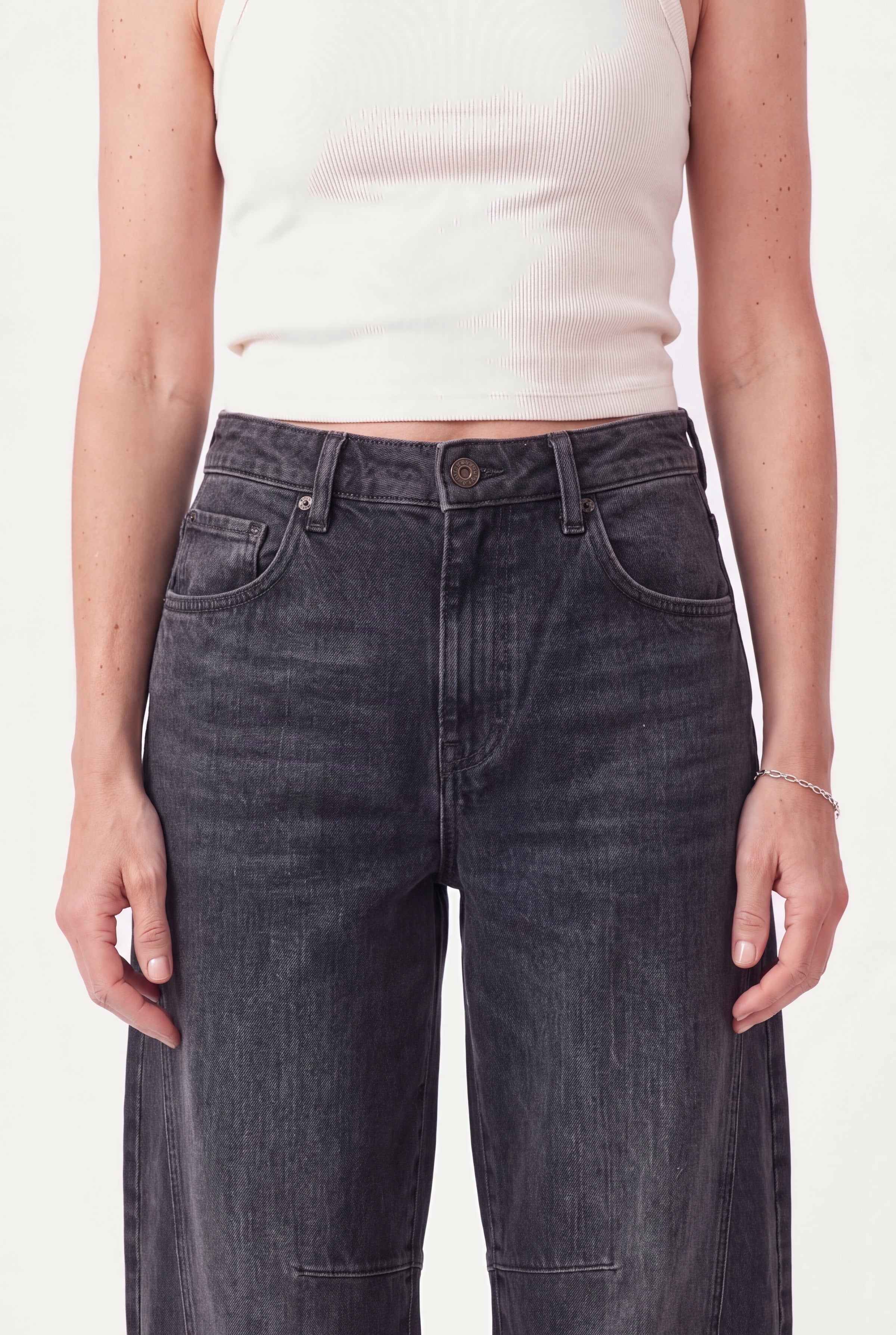 Detalje af sorte barrel leg jeans: mellemhøj talje, knap, lynlås og forlommer