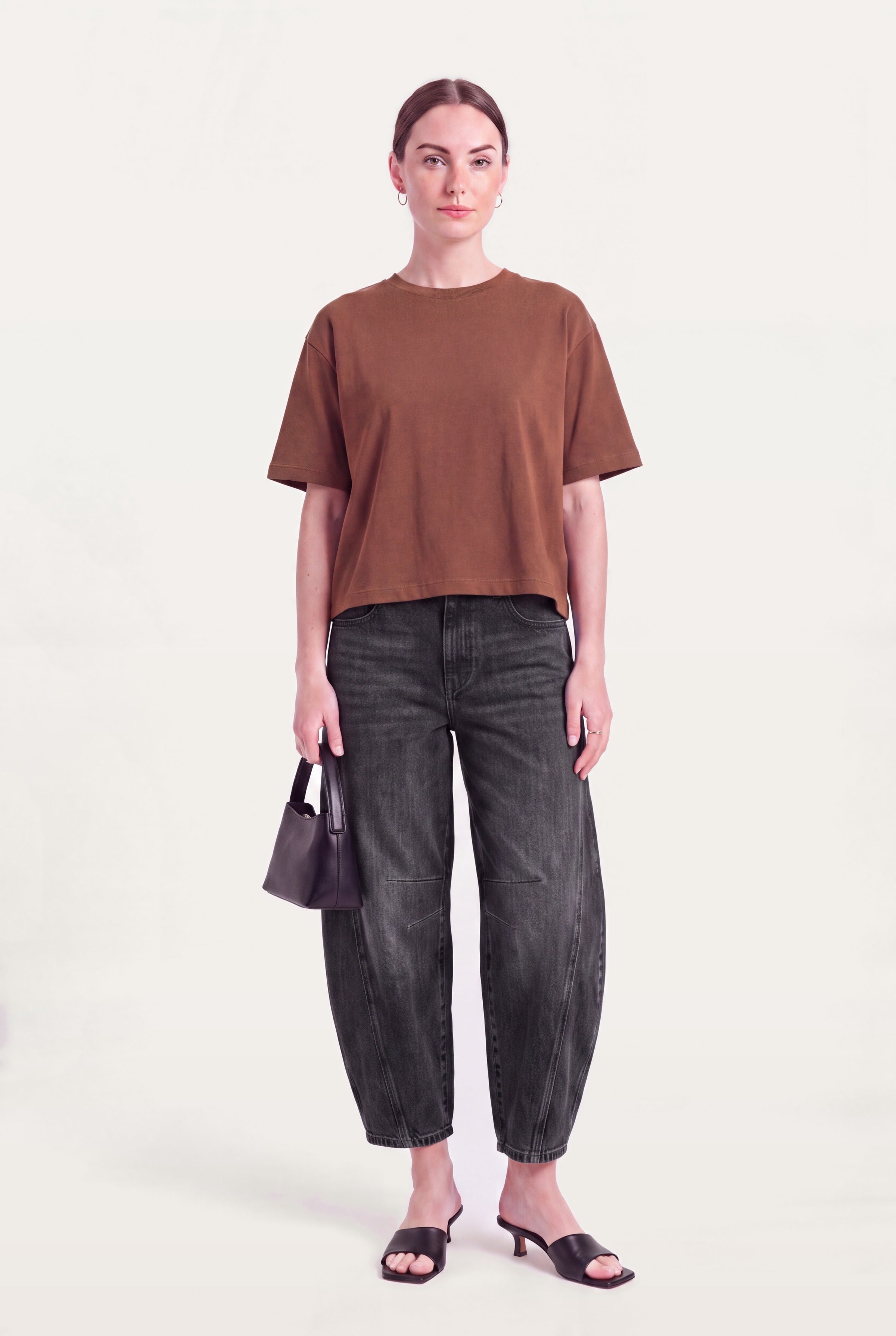 Barrel leg jeans dame i sort denim styles med brun top, lille taske og hæle