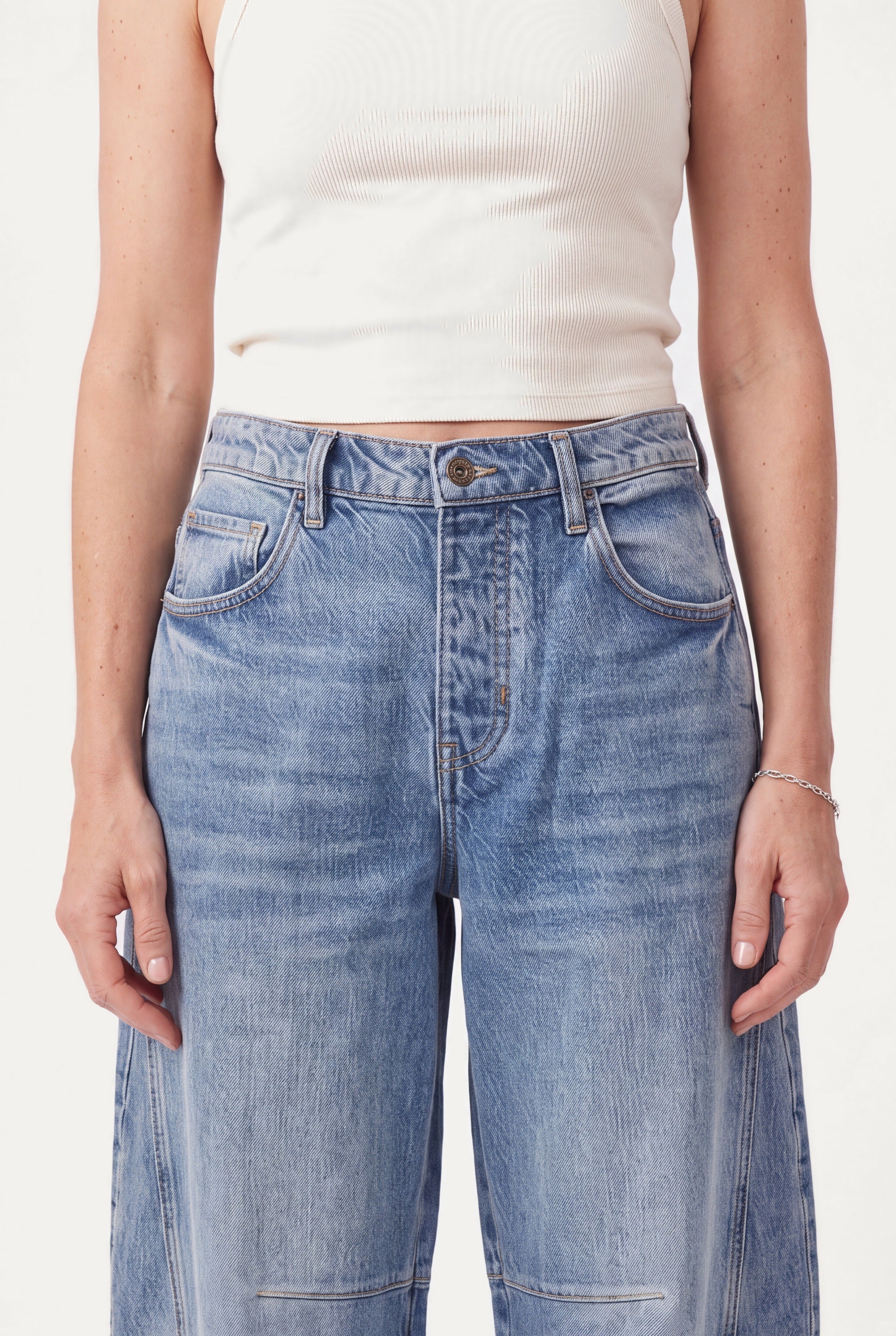 Detalje af barrel leg jeans: mellemhøj talje, knap, lynlås og forlommer