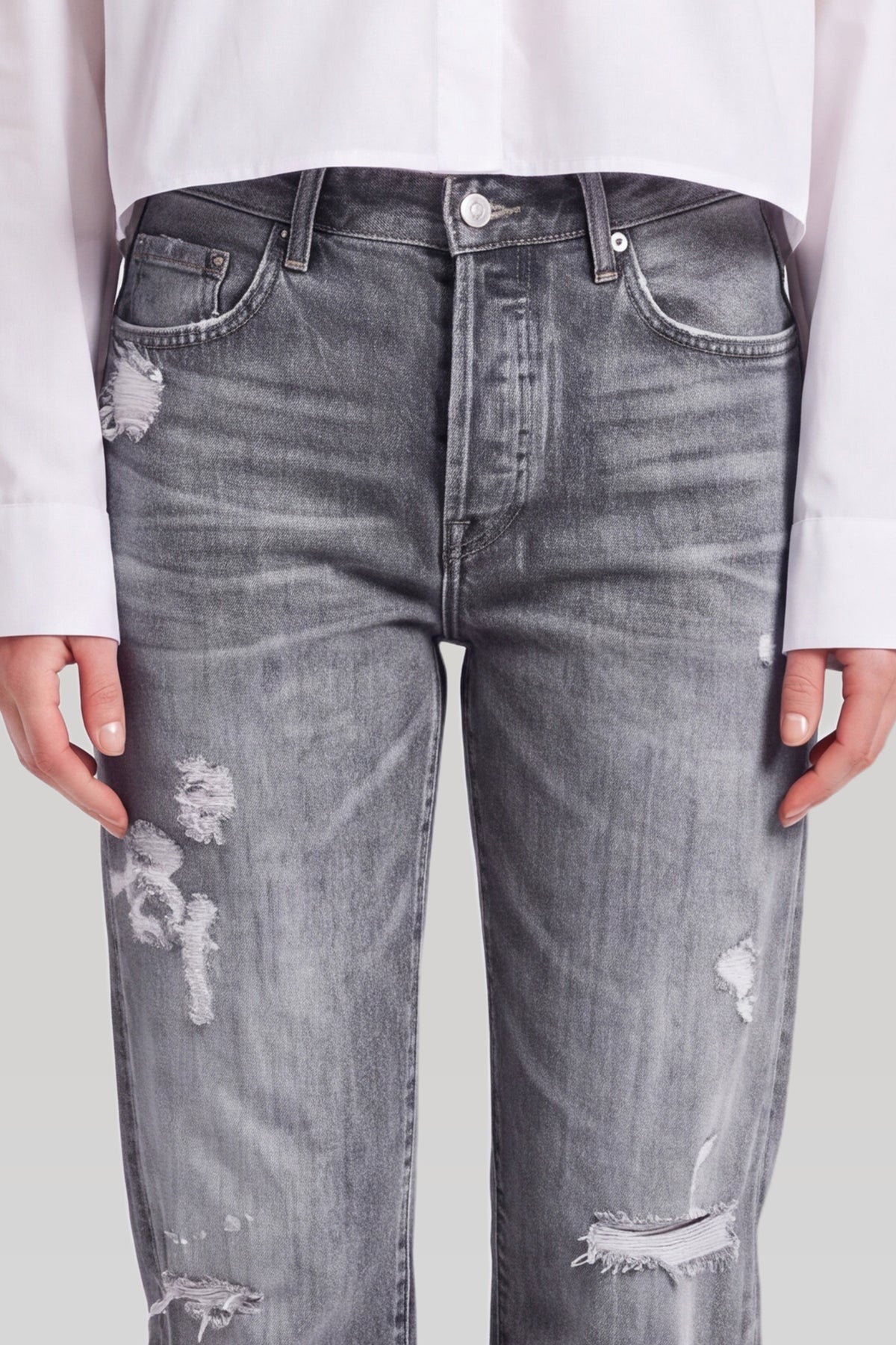 Nærbillede af grå ripped jeans: knaplukning, lomme og revner